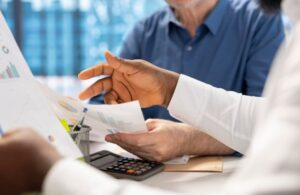 Equipe analisando relatórios de faturamento médico na Faturamax, com gráficos financeiros, documentos e calculadora sobre a mesa.