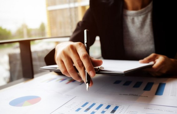 Profissionais de saúde analisam dados financeiros e indicadores de faturamento em uma reunião, com gráficos e documentos sobre a mesa.
