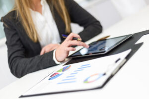 Mulher de negócios utiliza tablet em ambiente corporativo, representando a gestão e organização do faturamento médico.
