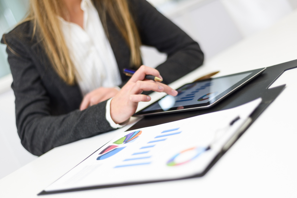 Mulher de negócios utiliza tablet em ambiente corporativo, representando a gestão e organização do faturamento médico.